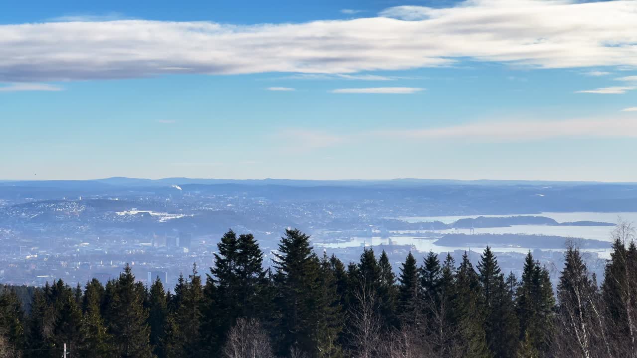 Cityscape view of downtown Olso Fjord Norway Norge aerial drone from Skimmer Oslo Holmenkoolen Ski Jump mid day sunny cloud forest Norwegian Sea Cross Country Skiing slope landscape pan left motion
