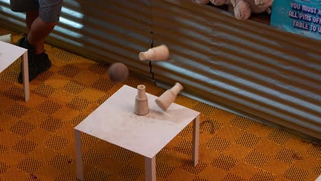 player throwing a ball, aiming at the milk bottles stacked on the table, a classic carnival knockdown game.