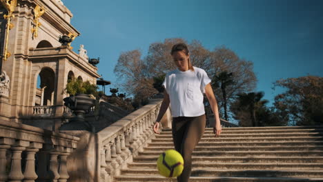 Caucasian-sporty-woman-doing-kick-ups-with-ball-outdoors.