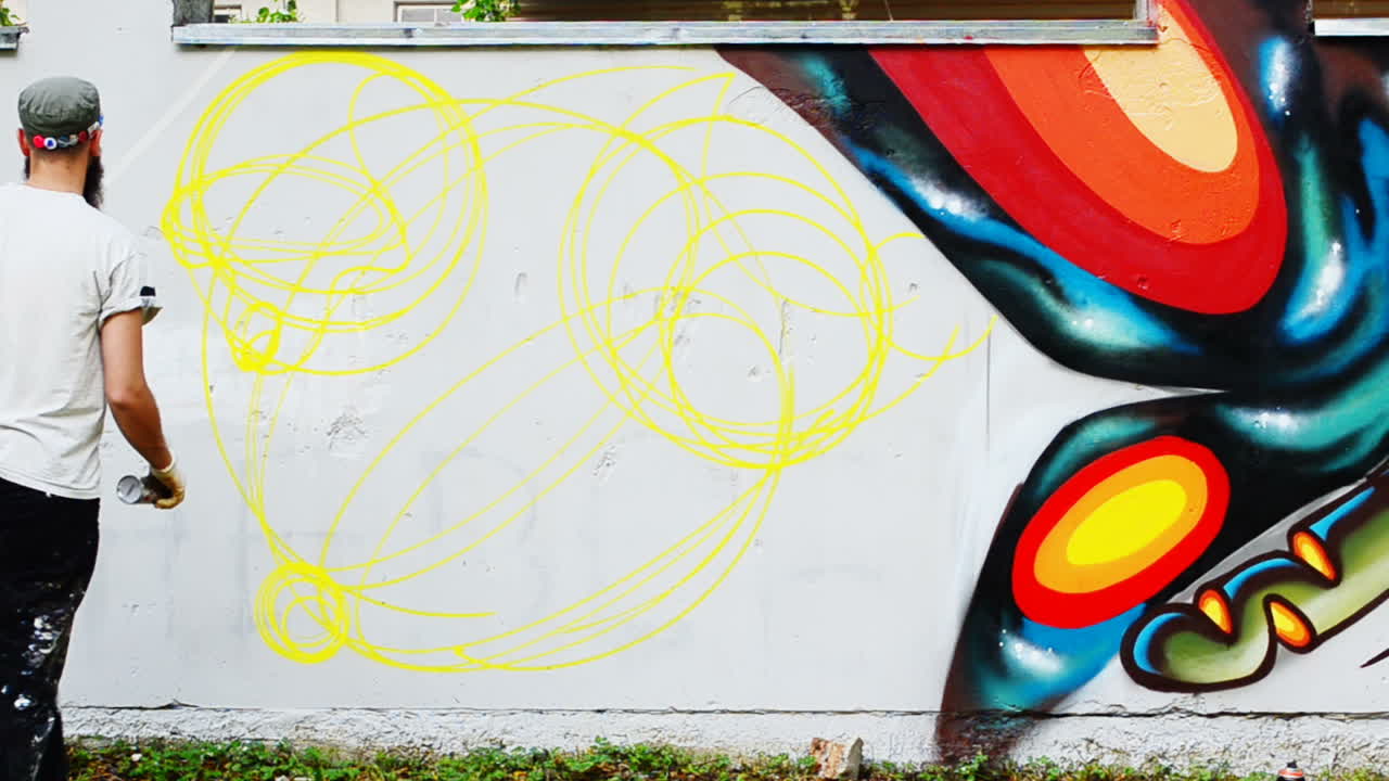 Kunstneren tegner graffiti på et gjerde. Abstrakt tegning.