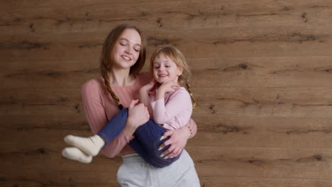 young lovely mother babysiter and little kid daughter jumping dancing on bed in modern house bedroom