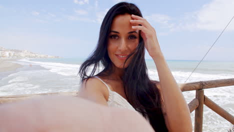 una joven bonita en la playa tomando una selfie.