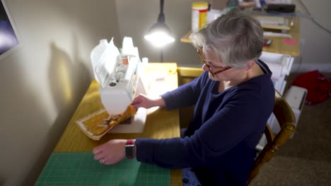 Mature woman making a potholder out of scrap quilting fabric - overhead view ORANGE SCRAPS SERIES