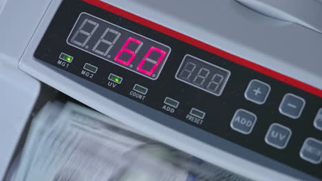 numbers growing quickly on the display of cash counting machine. american dollars being counted in equipment. close up.