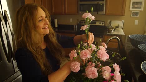 una anciana pelirroja pone una flor rosa en un ramo