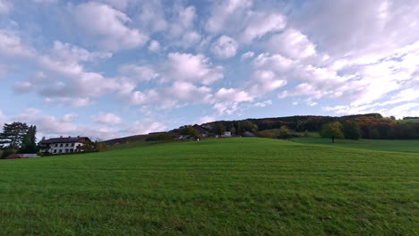 pan shot of wooden houses along green grass field along hill slope among rural countryside