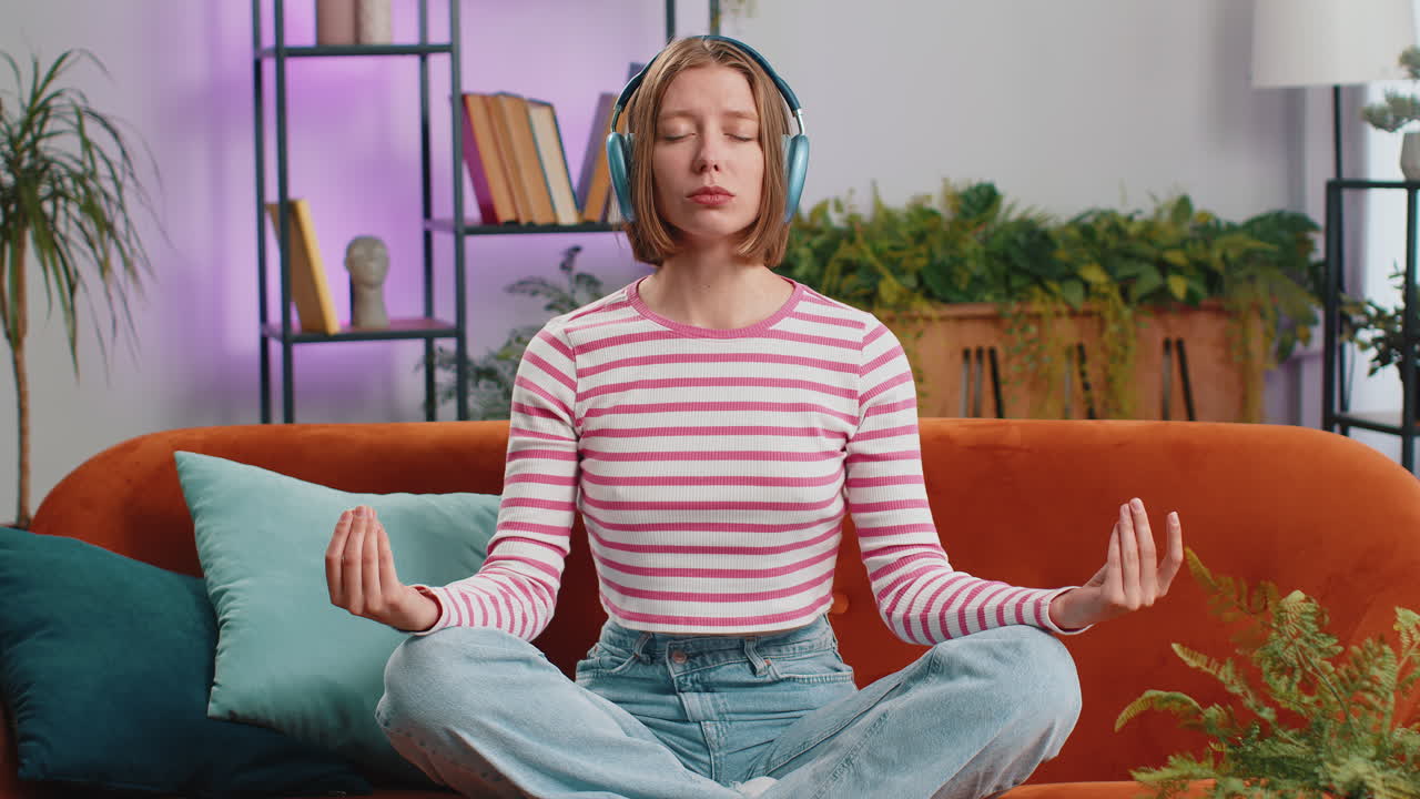 Woman breathes deeply eyes closed meditating with concentrated thoughts peaceful mind at home