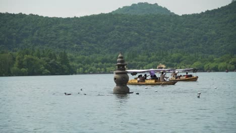 tourist boats on the west lake and one of the three stone pagodas from the three pools mirroring the moon hangzhou china