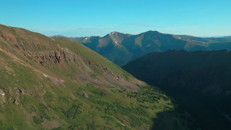 Aerial-cinematic-drone-early-morning-sunrise-trailhead-Grays-and-Torreys-14er-Peaks-Rocky-Mountains-Colorado-stunning-landscape-view-mid-summer-green-beautiful-snow-on-top-circling-left-movement