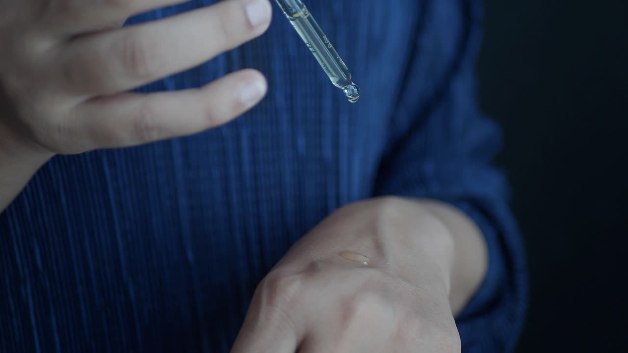 손 에 드로퍼 를 넣은 얼굴 세럼 을 바르는 여자