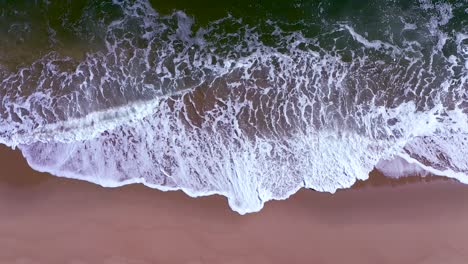 stationary-aerial-shot-of-ocean-waves-gently-breaking-over-a-sandy-beach