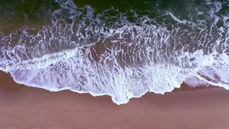 Toma-Aérea-Estacionaria-De-Las-Olas-Del-Océano-Rompiendo-Suavemente-Sobre-Una-Playa-De-Arena