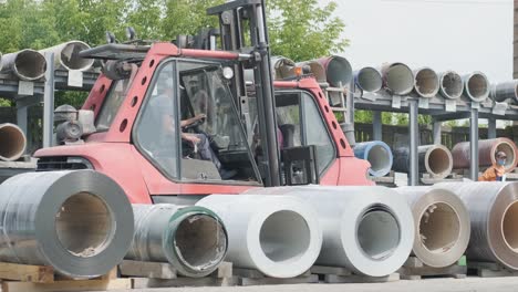 forklift driver loads rolls of steel sheet. industrial warehouse with rolls of steel sheet