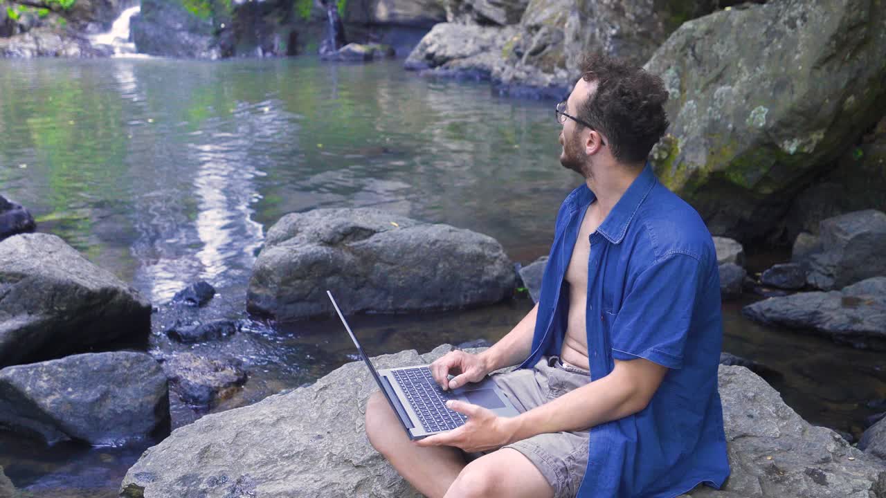 hombre de negocios trabajando con computadora en una roca en la naturaleza.