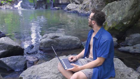 Businessman-working-with-computer-on-a-rock-in-nature.