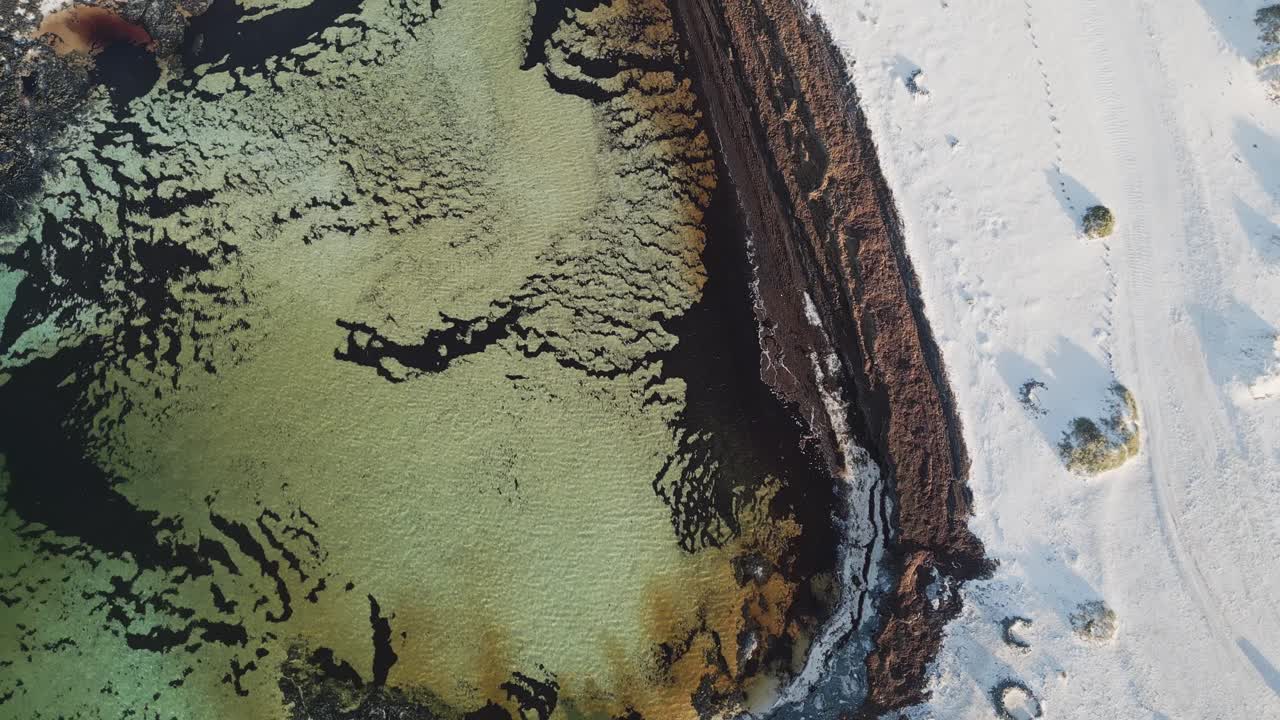 Overhead drone footage of the north coast of Fuerteventura, showing turquoise ocean meeting golden dunes in a dramatic natural landscape.