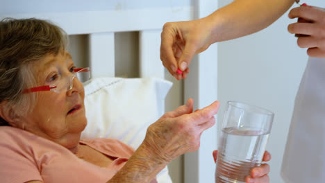 mujer mayor tomando pastillas del médico en la cama 4k