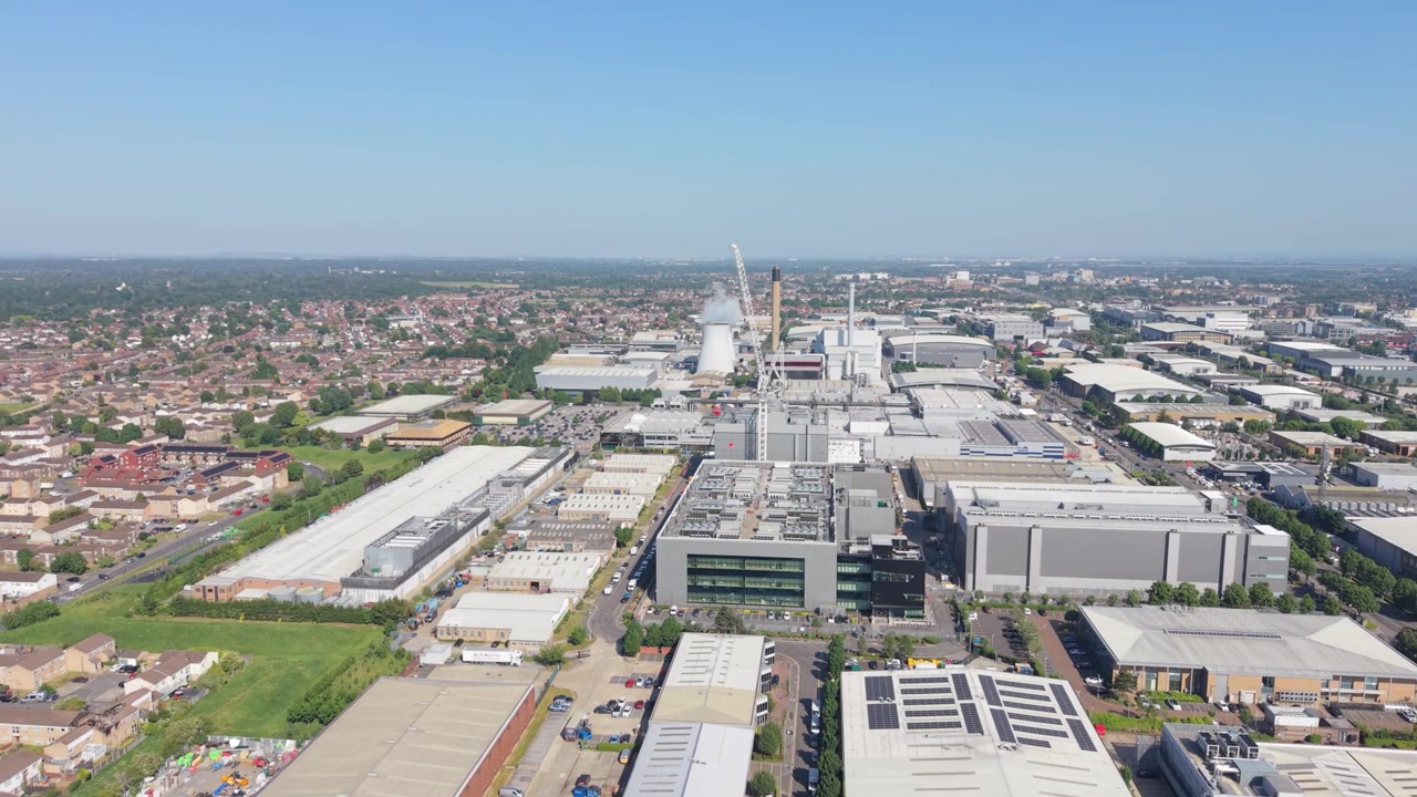 Una vista aerea cattura un enorme complesso di data center in un vasto parco industriale. Numerosi edifici moderni con pannelli solari sul tetto sono illuminati dalla luce del giorno.
