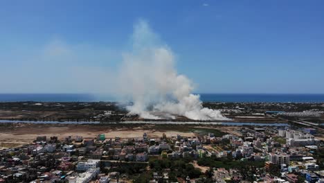 aerial over chennai during lockdown with smoke billowing in the background. follow shot