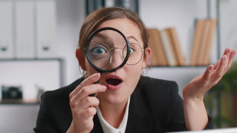 business woman holding magnifying glass near face, looking with big zoomed eye, searching, analysing