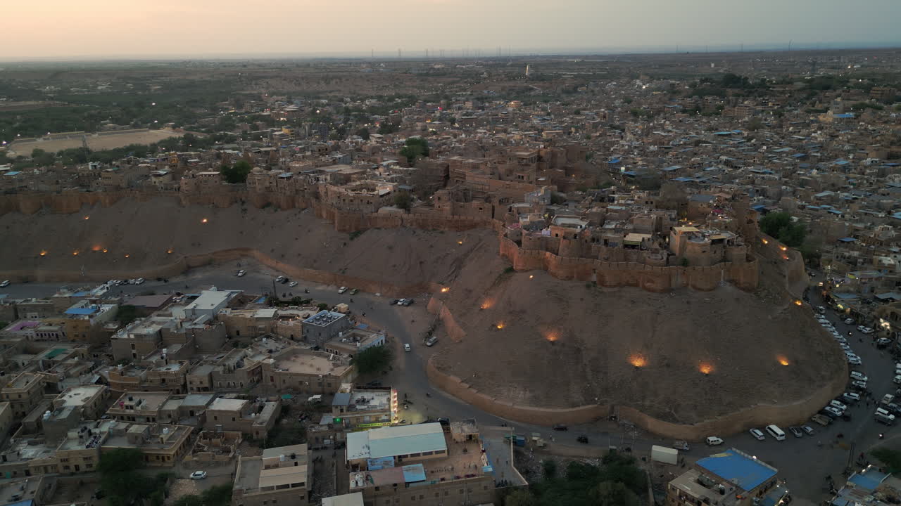 tomada lateral de un dron del fuerte de jaisalmer al atardecer, rodeado de casas y carreteras de tonos dorados en rajasthan, india 4k