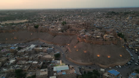 sideways drone shot of jaisalmer fort at sunset, surrounded by golden-hued houses and roads rajasthan india 4k
