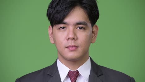 young handsome asian businessman against green background