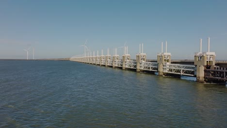 toma aérea acercándose y volando sobre la barrera de marejada ciclónica del este de scheldt en zelanda, los países bajos, en un hermoso día soleado