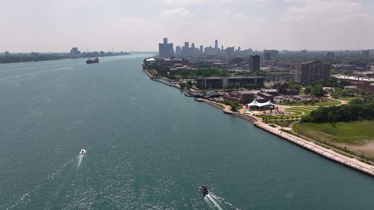 drone shot flying south along the Detroit River toward the Detroit skyline showing the Renaissance Center on a bright sunny but smoky hazy day affected by the Canadian wildfires