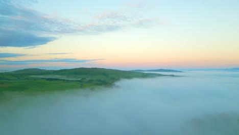 Campo-Cubierto-De-Niebla-Con-Una-Panorámica-Lenta-Que-Revela-Un-Banco-De-Niebla-Más-Grande,-árboles-Fantasmales-Y-Montañas-Distantes-Al-Amanecer.