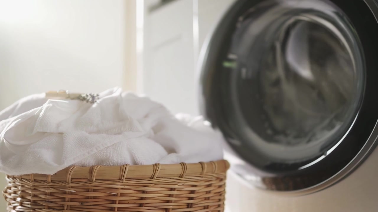 Wicker Basket with White Towels Beside a Running Washing Machine