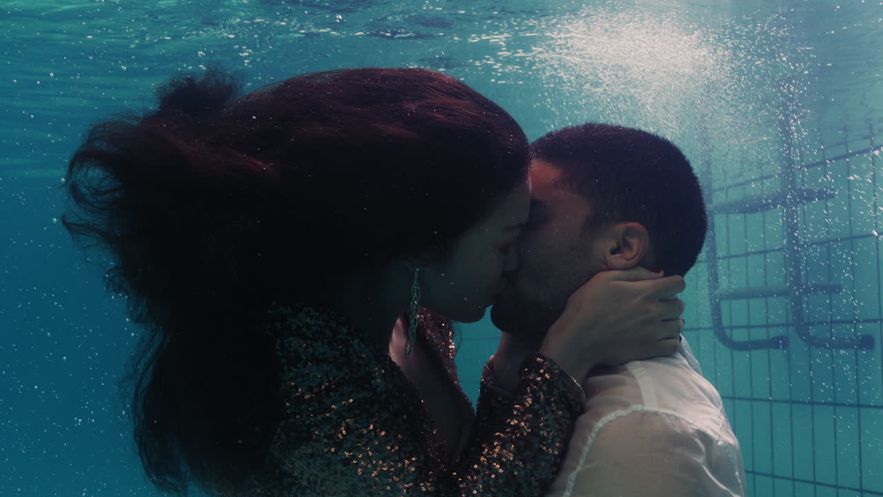 coppia romantica che si bacia sott'acqua in piscina con i vestiti giovani innamorati che si godono un bacio intimo amanti sommersi nell'acqua che galleggiano con bolle in un'intimità passionale