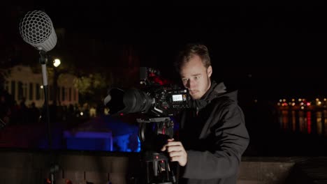 someone is filming a shoot with a cinema camera outside with a river in the background