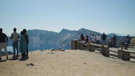 pan of tourists looking out at lake surrounded by mountains