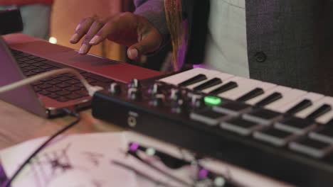 vrouw die synthesizer speelt tijdens de repetitie in de opnamestudio met haar band