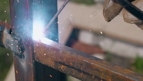 closeup worker uses welding instrument for connecting fence