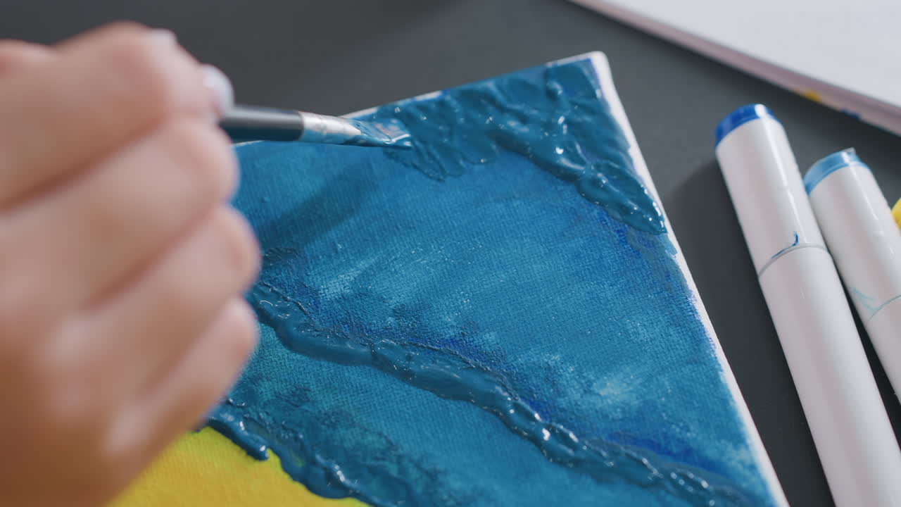 파란색으로 칠해진 캔버스 위의 질감이 있는 융기를 강조하는 섬세한 클로즈업 브러시, 밝은 정반사 하이라이트, 가장자리에 맞춰진 마커, 입체적인 효과를 위한 섬세한 탑코트, 집중된 손동작