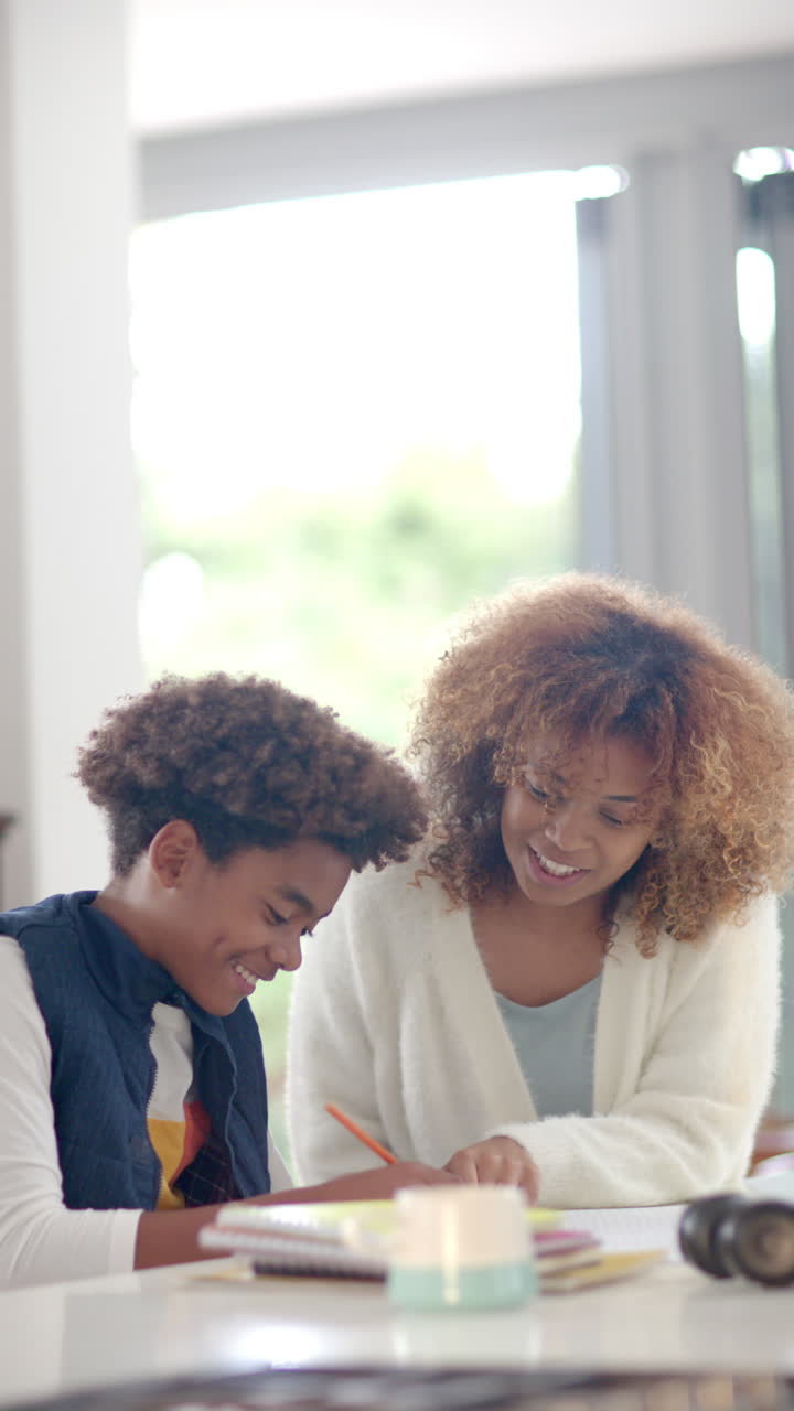 Vertical video of biracial mother helping her son with homework, slow motion
