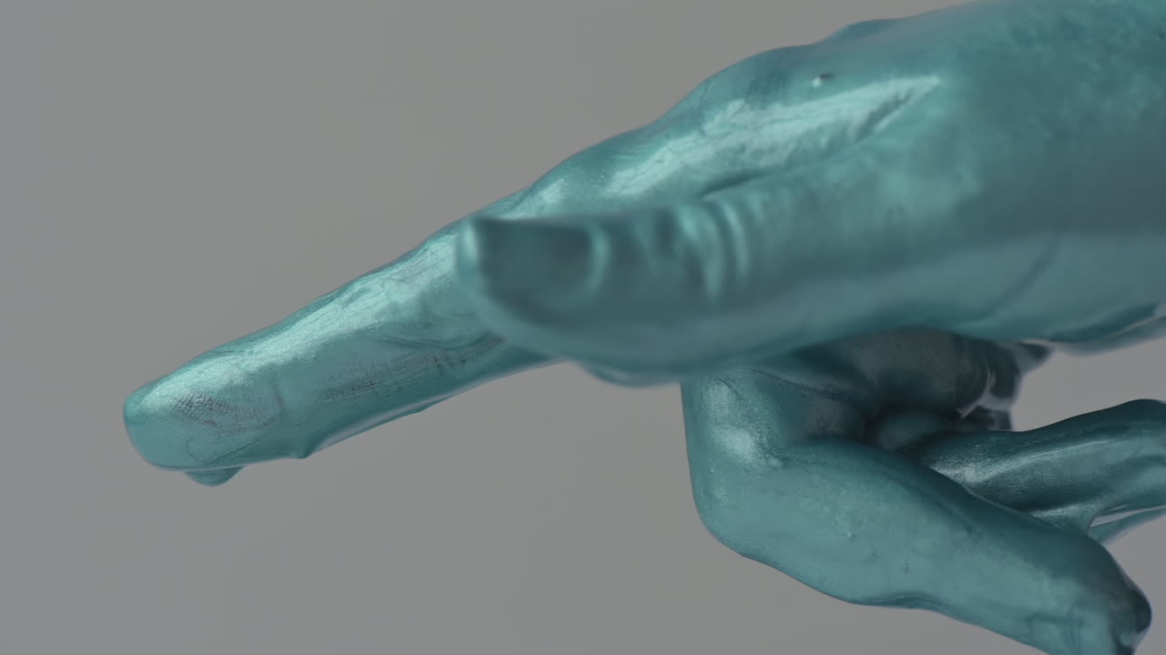 A close view of a beautifully painted hand sculpture shows intricate textures and vibrant colors. The artwork is displayed in a well-lit studio, enhancing its striking features and craftsmanship