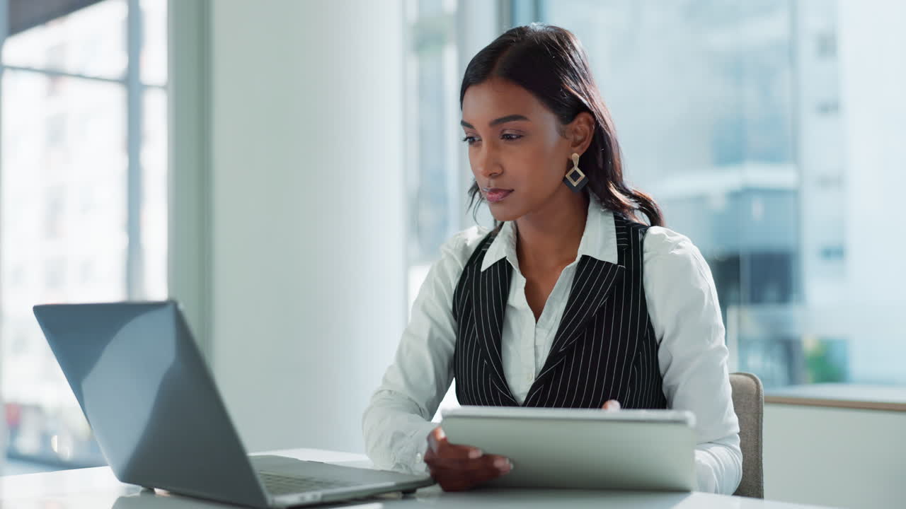 Businesswoman working on laptop and tablet in office