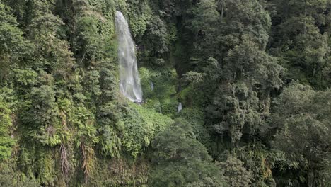 Dense-jungle-flight-to-dramatic-tall-waterfall-on-Lombok,-Indonesia