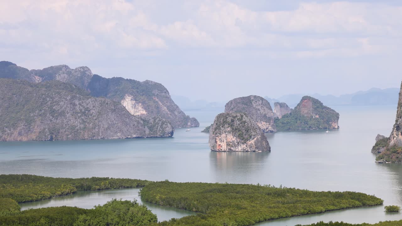 Panoramic view of towering limestone cliffs and calm waters under a clear sky in Phang Nga, Thailand