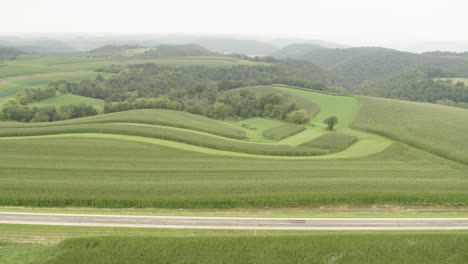 aerial, side view of rural countryside farm field road on an overcast day