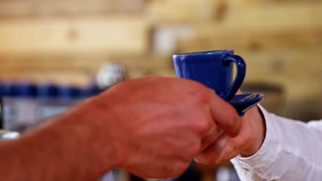 sección media del camarero que sirve café al cliente en el mostrador