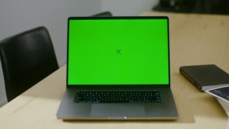 laptop with green screen on a wooden table