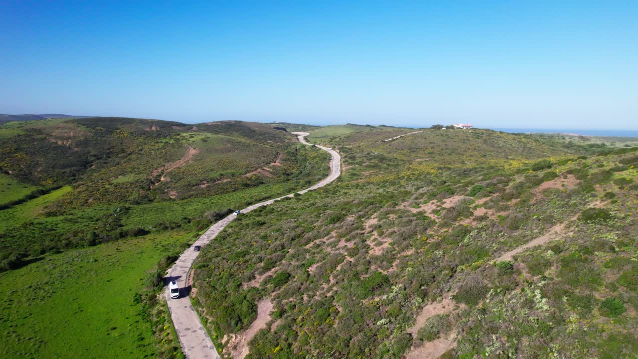 Vehicles Driving On Winding Road Along The Mountain Towards The Sea. - aerial shot