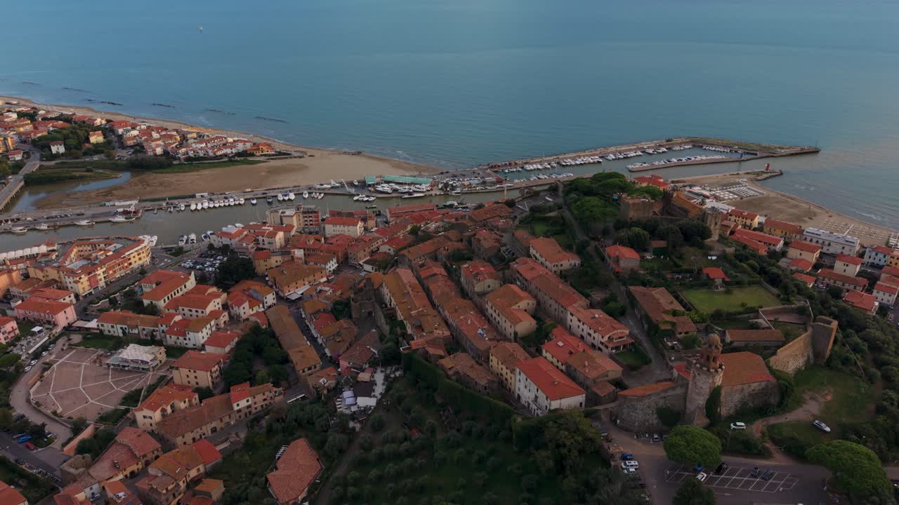 Castiglione delal Pescaia castle with views over the fishing port and open sea horizon. Scenic aerial