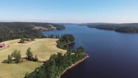 Aerial-Shot-Of-A-Farmhouse-On-A-Scenic-Lake-In-Sweden-During-Summer