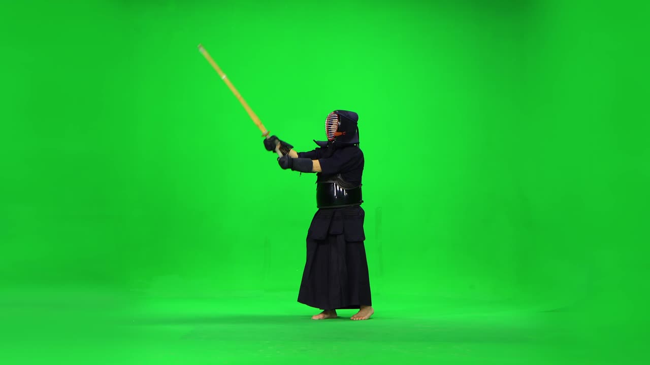 guerrero de kendo masculino practicando el arte marcial con el bokken de bambú en la pantalla verde