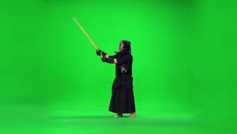 masculine kendo warrior practicing martial art with the bamboo bokken on green screen